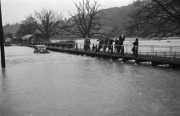 photo of the River Severn flooded in 1940, a car is being dragged by several men with a rope out of the river